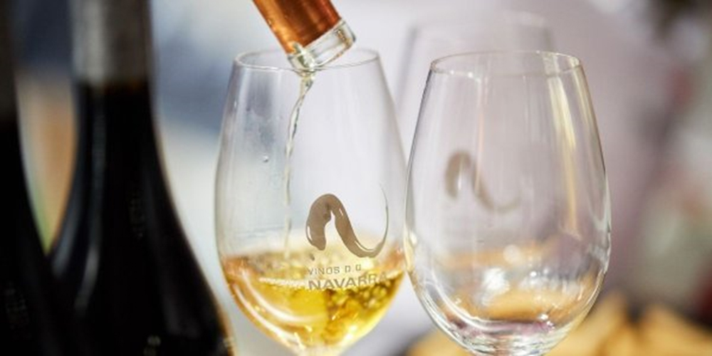 Sirviendo vino blanco en copas con el logo de la denominación de origen navarra