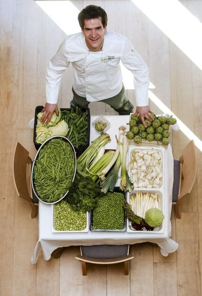Nacho Gómara del Restaurante Verduarte posa en una mesa llena de verduras en crudo de navarra